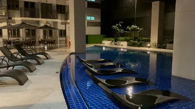 a swimming pool in a building with tables and chairs at S Residences Luxury Unit in Manila