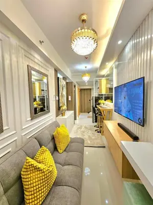 a living room with a couch with yellow pillows at Sky PortLuxe Studio Near MOA in Manila