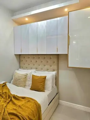 a bed in a room with white cabinets at Sky PortLuxe Studio Near MOA in Manila