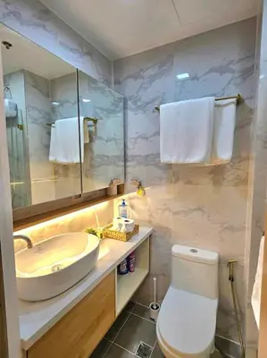 a bathroom with a sink and a toilet and a mirror at Sky PortLuxe Studio Near MOA in Manila