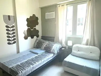 a living room with a bed and a window at The Rochester, Bridgeview Tower - 1BR Apartment in Manila