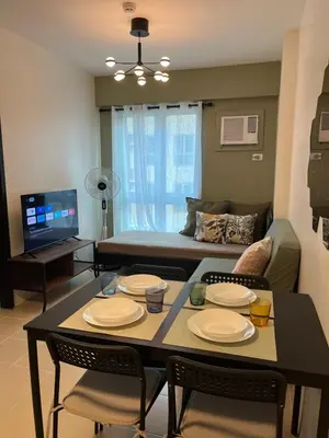 a living room with a table and chairs and a couch at The Rochester, Bridgeview Tower - 1BR Apartment in Manila