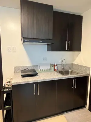 a kitchen with black cabinets and a sink at The Rochester, Bridgeview Tower - 1BR Apartment in Manila