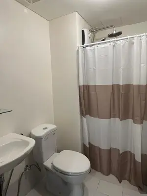 a bathroom with a toilet and a shower curtain at The Rochester, Bridgeview Tower - 1BR Apartment in Manila