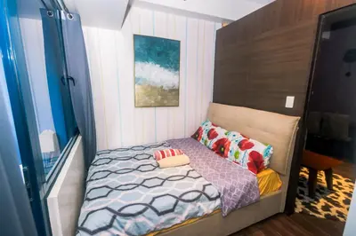 a small bedroom with a bed with a wooden headboard at Penthouse Fantasy in Manila