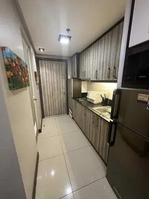 a small kitchen with a refrigerator and a sink at Shell Residences Staycation near SM MOA in Manila