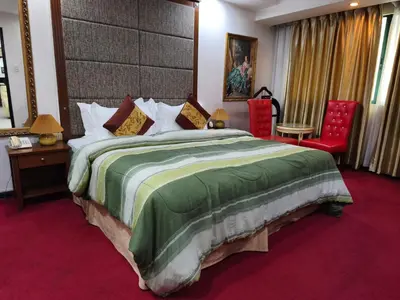 a bedroom with a large bed and two red chairs at Lido De Paris Hotel in Manila