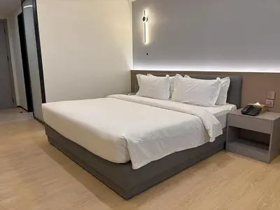 a bedroom with a large bed with white sheets and pillows at Lido De Paris Hotel in Manila