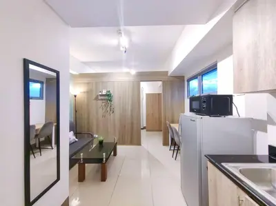 a kitchen and living room with a refrigerator and a table at 1BR Condotel with Balcony at FAME Residences #FM11 in Manila