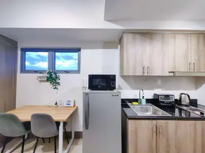 a kitchen with a table and a refrigerator and a sink at 1BR Condotel with Balcony at FAME Residences #FM11 in Manila