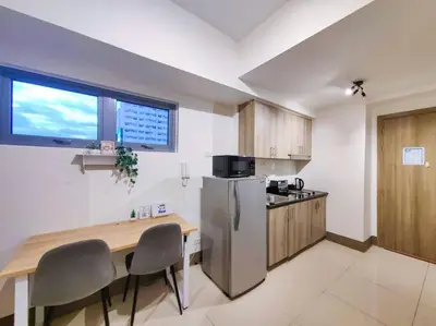 a kitchen with a table and a stainless steel refrigerator at 1BR Condotel with Balcony at FAME Residences #FM11 in Manila