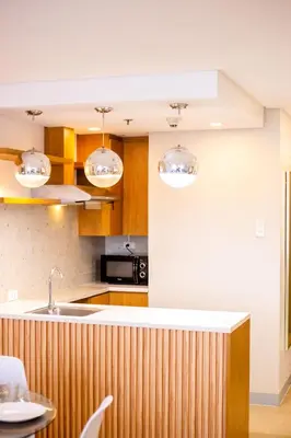 a kitchen with wooden cabinets and a sink and lights at Antel Spa & Serenity Suites in Manila