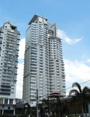 a tall white building with palm trees in front of it at Antel Spa & Serenity Suites in Manila