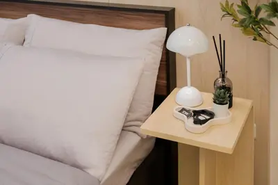 a bed with a side table with a lamp and a side table at Eastwood City Cozy Designer Studio Long Stay Friendly Walk to Mall in Manila