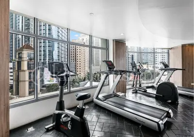 a gym with two treadmills and ellipticals in front of windows at Eastwood City Cozy Designer Studio Long Stay Friendly Walk to Mall in Manila