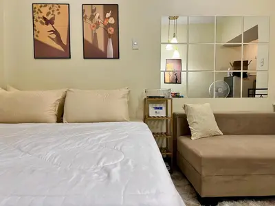 a bedroom with a bed and a couch at Staycation Condotels for Travellers Near Airport in Manila