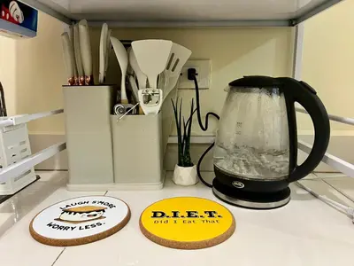 a kitchen counter with a jug of water and two signs at Staycation Condotels for Travellers Near Airport in Manila