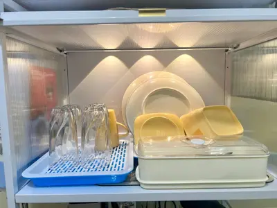 a refrigerator filled with dishes and plates on a shelf at Staycation Condotels for Travellers Near Airport in Manila