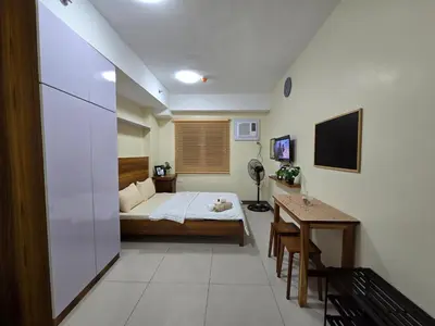 a bedroom with a bed and a desk in it at Staycation Condotels for Travellers Near Airport in Manila