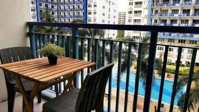 a table and chairs on a balcony with a view of a pool at South Pad Staycation Sea Residences SM Mall of Asia Tower A, B and E in Manila