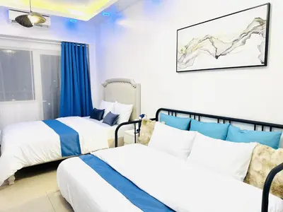 two beds in a room with blue and white at Shore Residences by Premier Suites in Manila