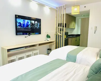 two beds in a hotel room with a flat screen tv at Shore Residences by Premier Suites in Manila