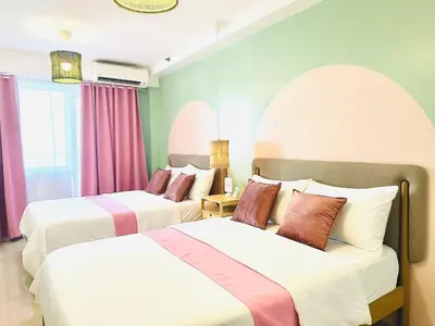 two beds in a room with pink and white at Shore Residences by Premier Suites in Manila