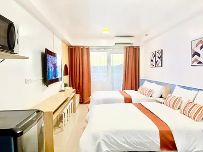a hotel room with two beds and a flat screen tv at Shore Residences by Premier Suites in Manila