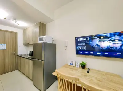 a kitchen with a table and a refrigerator and a tv at 1BR Condotel with Balcony at FAME Residences #FM15 in Manila