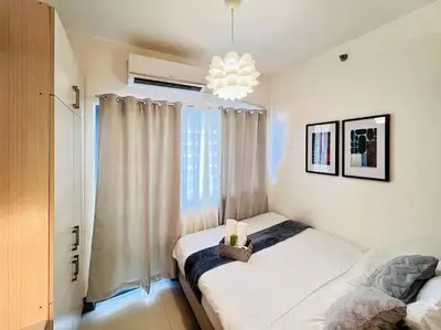 a bedroom with a bed and a large window at 1BR Condotel with Balcony at FAME Residences #FM15 in Manila