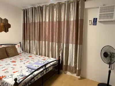 a bedroom with a bed and a window with curtains at Green Glory Staycation in Amadeo in Cavite