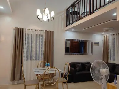 a living room with a table and chairs and a staircase at Green Glory Staycation in Amadeo in Cavite