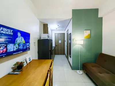 a living room with a couch and a tv in a room at 1BR Condotel with Balcony at FAME Residences #FM18 in Manila