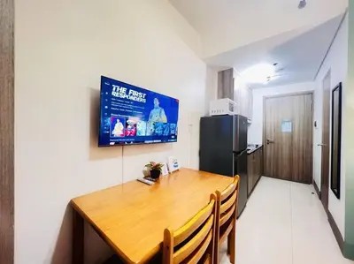 a kitchen with a wooden table and a refrigerator at 1BR Condotel with Balcony at FAME Residences #FM18 in Manila