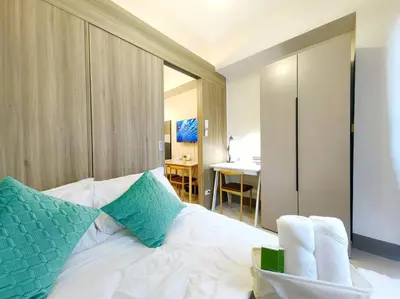 a bedroom with a white bed with green pillows at 1BR Condotel with Balcony FAME Residences #FM24 in Manila