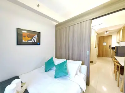 a bedroom with a white bed with blue pillows at 1BR Condotel with Balcony FAME Residences #FM24 in Manila
