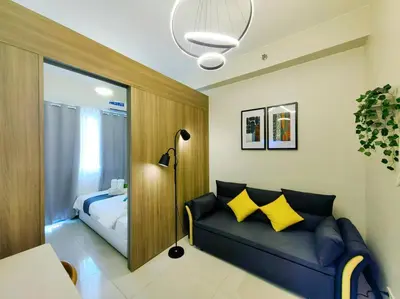 a living room with a blue couch with yellow pillows at 1BR Condotel with Balcony FAME Residences #FM24 in Manila