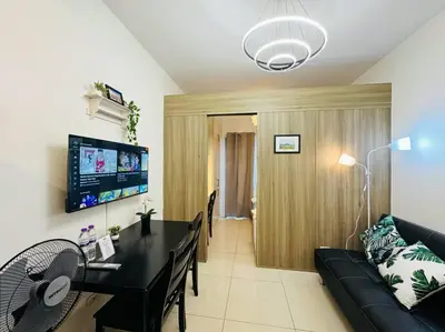 a living room with a black couch and a table at 1BR Condotel with Balcony at FAME Residences #FM41 in Manila