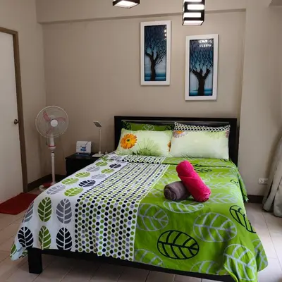 a bedroom with a green and white bed with red pillows at LDN Secret Crib - Two Palm Tree Newport City in Manila