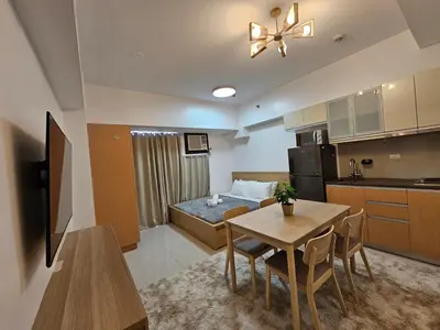 a room with a bed and a table and a kitchen at Affordable Condo Suite with 150mbps WIFI in Manila