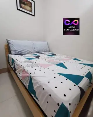 a bed with a comforter on top of it at Mall of Asia Pasay Shore 3 residences tower 2 in Manila
