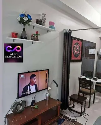 a living room with a flat screen tv and a table at Mall of Asia Pasay Shore 3 residences tower 2 in Manila