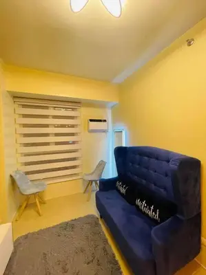 a living room with a blue couch and a chair at Meteor Suites in Manila