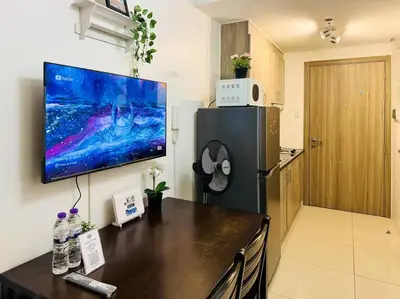 a kitchen with a refrigerator and a television on a wall at 1BR Condotel with Balcony at FAME Residences #FM42 in Manila