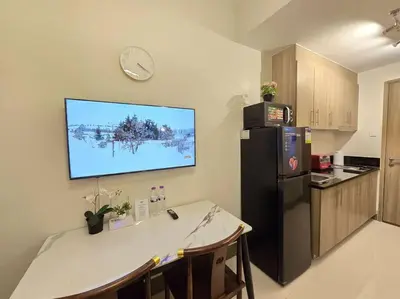 a kitchen with a black refrigerator and a clock on the wall at 1BR Condotel with Balcony at FAME Residences #FM44 in Manila