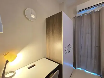 a room with a desk with a lamp and a clock at 1BR Condotel with Balcony at FAME Residences #FM46 in Manila