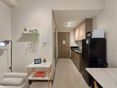 a living room with a black refrigerator and a kitchen at 1BR Condotel with Balcony at FAME Residences #FM46 in Manila