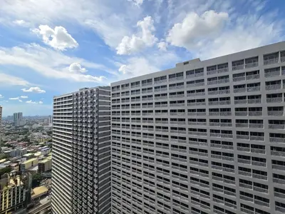 a tall white building with a city in the background at 1BR Condotel with Balcony at FAME Residences #FM46 in Manila