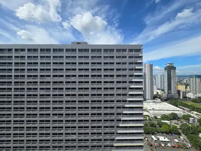 a tall building with a city in the background at 1BR Condotel with Balcony at FAME Residences #FM46 in Manila