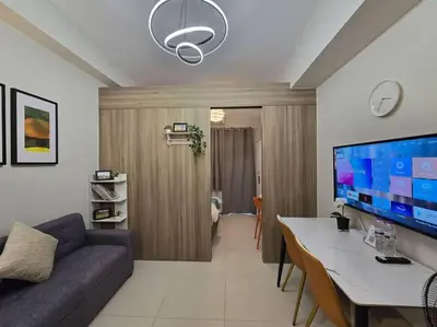 a living room with a couch and a large screen tv at 1BR Condotel with Balcony at FAME Residences #FM45 in Manila